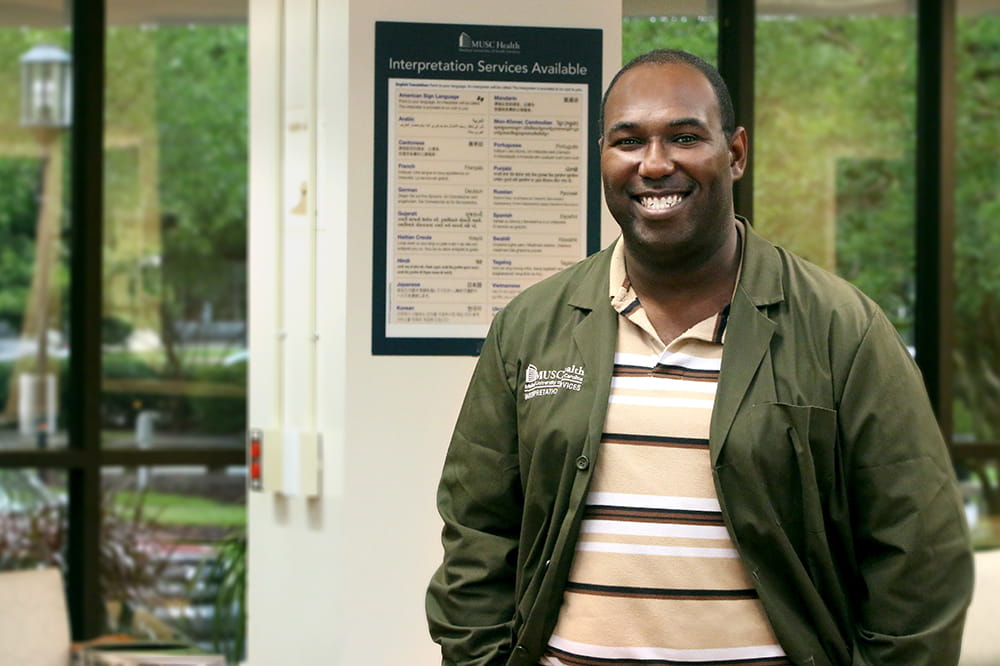 man stands in front of sign showing languages available for interpretation