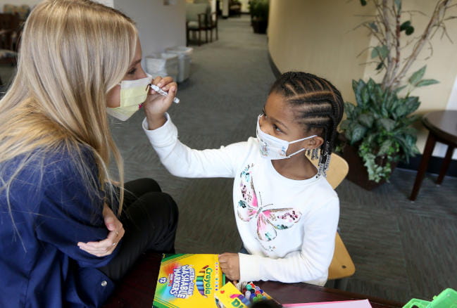 MUSC Arts in Healing art therapist working with child coloring hospital mask in waiting room