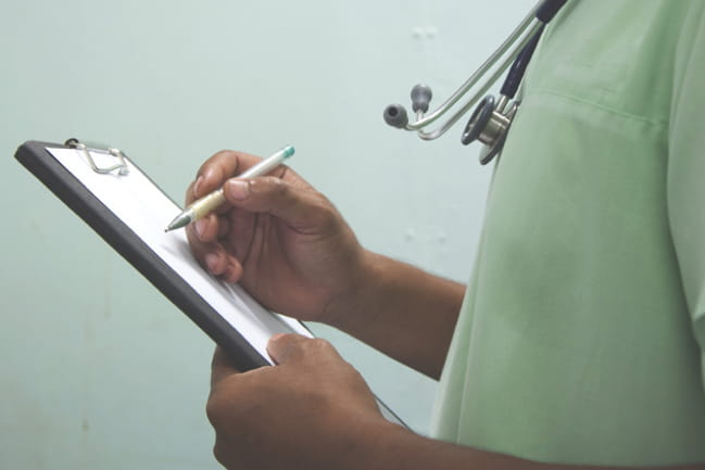 Doctor's hands holding a clipboard close up.