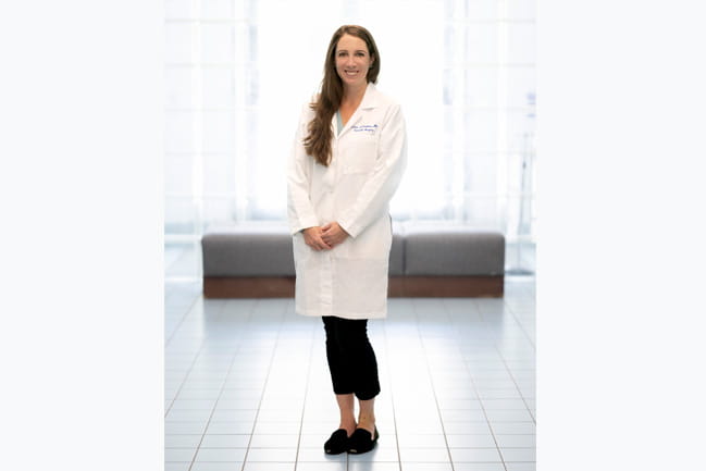 Dr. Donahue stands in a white coat in the lobby of the psychiatry department at MUSC Health