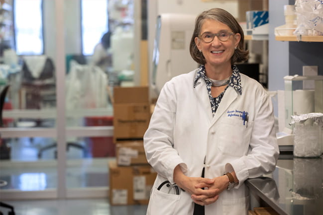 Dr. Susan Dorman leaning against a table in her lab. 