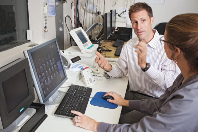 Dr. Brett E. Froeliger speaking to a colleague at a computer