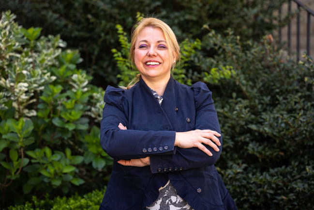 Dr. Sophie Paczensny stands in front of a bush. 