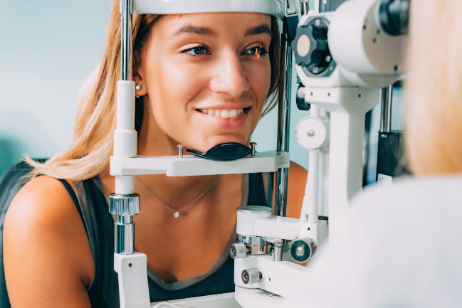 Person resting their chin in a head stability device during an eye exam.