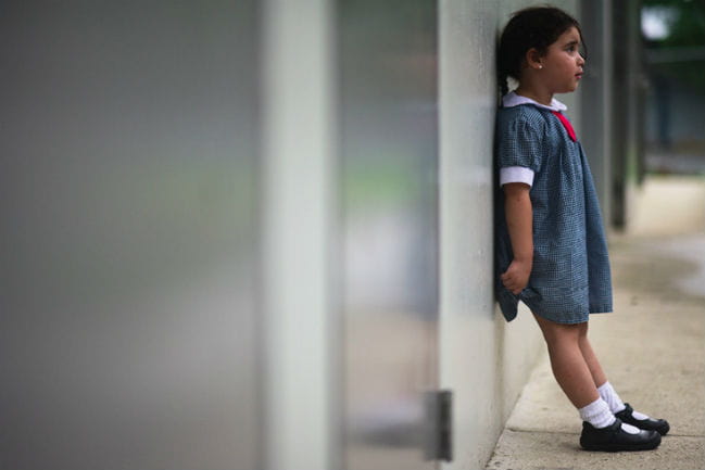 Little girl leaning against a wall. 