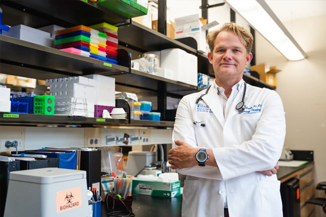 Dr. John Wrangle in his white coat standing in his lab.