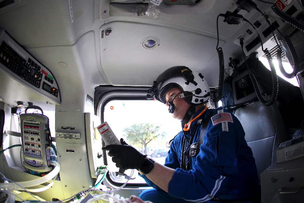 A flight nurse administers care to a patient in flight