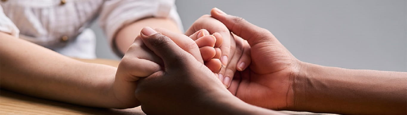 Image of two people holding hands in a supporting manner.