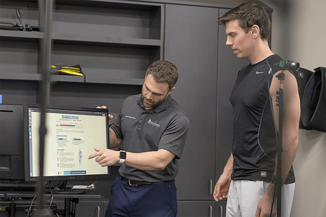 Client receiving movement advice by technician pointing at analysis screen